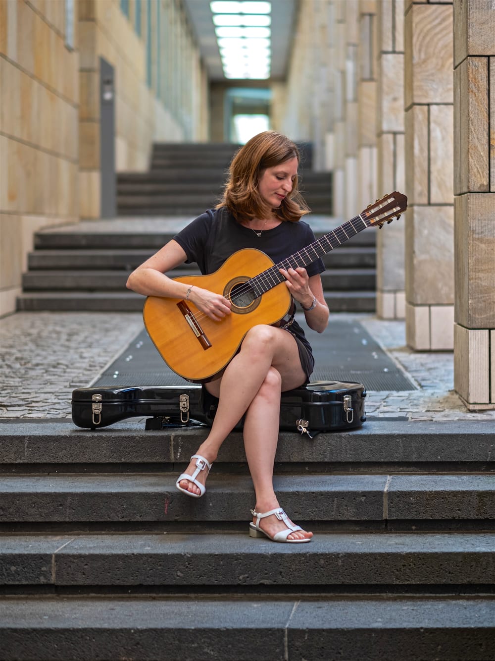 Gabi Schneider sitzt auf einer Treppe und spielt Gitarre
